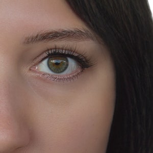 Puede incluir: Primer plano de la cara de una mujer, mostrando su ojo izquierdo con iris verde y cabello largo casta&ntilde;o oscuro.