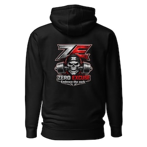 Puede incluir: Sudadera con capucha negra con un gráfico que dice "ZERO EXCUSE - Embrace the suck". El diseño presenta una calavera con un casco de halterofilia, con pesas. Las letras "ZE" son rojas y blancas.