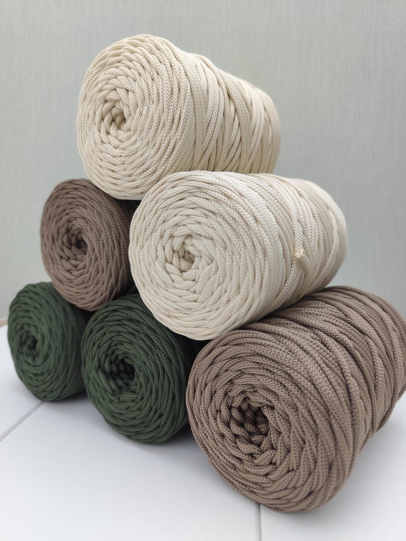 Op de afbeelding: Een set van drie keramische mokken met een gespikkelde, matte afwerking. De mokken zijn in de kleuren cr&egrave;me, lichtgrijs en donkergrijs. Elke mok heeft een eenvoudig, minimalistisch ontwerp en een afgeronde handgreep.