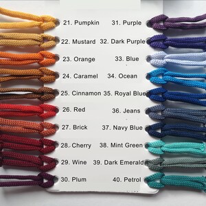 Op de afbeelding: Een kleurenkaart met een verscheidenheid aan koordkleuren, waaronder Pompoen, Mosterd, Oranje, Karamel, Kaneel, Rood, Baksteen, Kers, Wijn en Pruim. Extra kleuren zijn Paars, Donkerpaars, Blauw, Oceaan, Koningsblauw, Jeans, Marineblauw, Mintgroen, Donkergroen en Petrol.