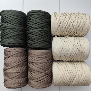 May include: Six spools of yarn in three colors: dark green, light brown, and cream. The spools are arranged in three rows of two.