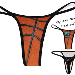 May include: Orange and black thong underwear with a basketball design. The thong features a basketball texture and black lines, with black straps. Additional images show the thong with the number 23 on the front and back.