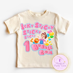May include: Cream-colored toddler t-shirt with a colorful graphic. The graphic includes the text "Icky Sticky Sticky 1 Bubble Gum" in pink bubble letters, along with cartoon characters and balloons. The shirt is designed for a child's first birthday.