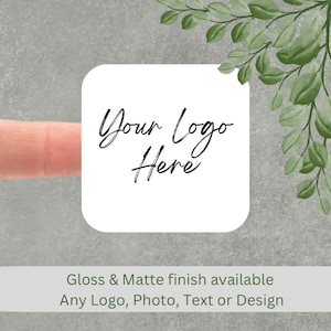 May include: White square sticker with the text "Your logo Here" in black cursive writing. Gloss and matte finish available. Any logo, photo, text or design.