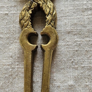 May include: A gold-colored metal nutcracker shaped like a rooster. The nutcracker has a detailed design and is in good condition.