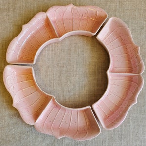 Puede incluir: Un juego de cuatro platos para servir de cerámica rosa con un acabado moteado. Los platos tienen forma de pétalos de flores y encajan para formar un círculo.