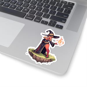 May include: A sticker featuring a cartoon witch with red skin, wearing a black hat and dress, holding a flame. The witch stands on a small, grassy island. The sticker is placed on a laptop.