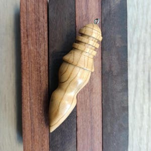 May include: A wooden ornament with a unique, organic shape and a layered top. The ornament is light brown and has a smooth, polished finish.