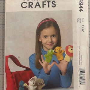 May include: McCall's Crafts sewing pattern envelope M4944 for finger puppets and a bag. The cover features a child wearing a blue shirt and a red headband, displaying green, yellow, and lion finger puppets, with a red bag and other puppets.