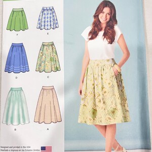 Può includere: Modello di cucito Simplicity 1369 H5 con modelli di gonne. Il modello presenta illustrazioni di gonne verdi, blu e con motivi floreali. L'immagine mostra anche una donna che indossa una gonna floreale. Il testo sul modello recita "SIZE U.S. 6-14" e "TAILLE FR. 34-42".