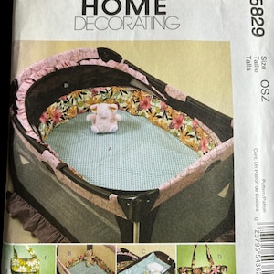 Op de afbeelding: Een naaipatroon voor een box, een luiertas en andere babyaccessoires. Het patroon is van McCall's Home Decorating en is voor maat OSZ. Het patroon bevat instructies voor het maken van een boxinleg, een luiertas, een verschoningsmat en een speelgoedtas.
