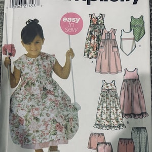 May include: A Simplicity sewing pattern envelope 5226, size A 3,4,5,6,7,8, featuring illustrations of various dresses, tops, and trousers. The cover displays a child wearing a floral dress, the text easy to sew, and the brand name Wrights.