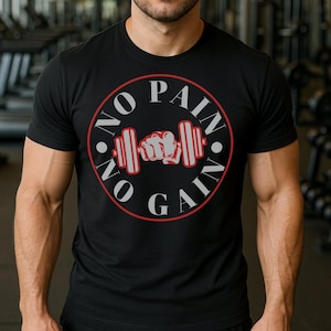 Peut inclure: T-shirt noir à col rond avec un motif rouge et blanc. Le motif représente une barre de musculation et un poing serré à l'intérieur d'un cercle rouge, avec les mots "NO PAIN NO GAIN" en lettres blanches.
