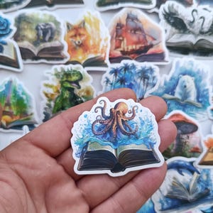 Pode incluir: Uma coleção de autocolantes coloridos com várias ilustrações. Um autocolante mostra um polvo a emergir de um livro com salpicos de água. Outros mostram cenas como uma raposa, um dinossauro e um navio.
