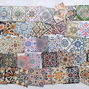 Könnte beinhalten: Eine Sammlung dekorativer quadratischer Fliesen mit aufwendigen floralen und geometrischen Mustern in verschiedenen Farben, darunter Blau, Orange und Grün. Die Fliesen sind auf einer weißen Oberfläche angeordnet und zeigen eine Vielzahl von Designs.