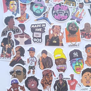 Könnte beinhalten: Eine Sammlung farbenfroher Aufkleber mit Porträts von Hip-Hop-Künstlern. Die Aufkleber zeigen verschiedene Rapper und Musiker, einige mit Text wie "MADE IN THE 90S" und "GOLF". Die Aufkleber befinden sich auf einem weißen Hintergrund.