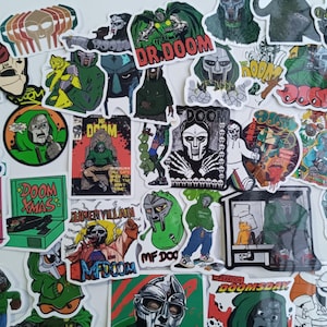 Könnte beinhalten: Eine Sammlung farbenfroher Aufkleber mit verschiedenen Illustrationen einer maskierten Figur in Grün und Silber. Einige Aufkleber enthalten den Text "DR. DOOM", "DOOM XMAS" und "MF DOOM".