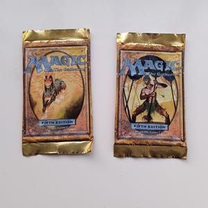 Può includere: Due bustine sigillate di Magic: The Gathering Fifth Edition con bordi in lamina dorata. Ogni confezione riporta il logo del gioco, la scritta Fifth Edition e 15 Tradable Game Cards. Il pacchetto a sinistra mostra un cavallo, quello a destra una figura.
