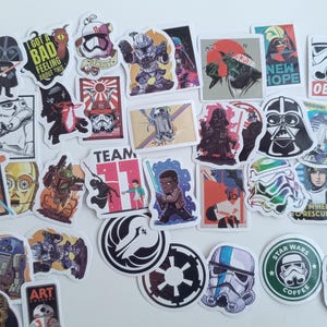 Può includere: Una collezione di adesivi a tema Star Wars con vari personaggi, loghi e citazioni. Gli adesivi sono di varie forme e dimensioni, con un bordo bianco. Alcuni adesivi includono il testo "NEW HOPE", "OBEY" e "STAR WARS COFFEE".