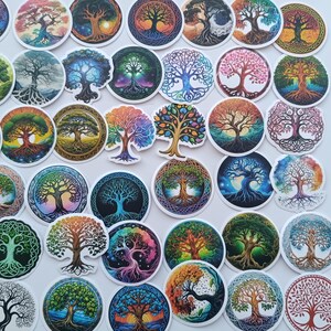 May include: A selection of circular stickers displaying tree of life designs. The stickers depict trees with detailed root and branch patterns, in a range of colours including green, blue, orange, and purple. The stickers are arranged on a white surface.