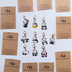 Pode incluir: Uma coleção de chaveiros com tema de panda e cartões correspondentes. Os chaveiros apresentam designs de pandas em várias poses e cores. Os cartões exibem o texto "You're Pandastic!" com uma mensagem inspiradora.