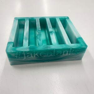 May include: A green and white marbled resin mold with five rectangular compartments. The mold has the text "#jakeblanks" on the bottom.