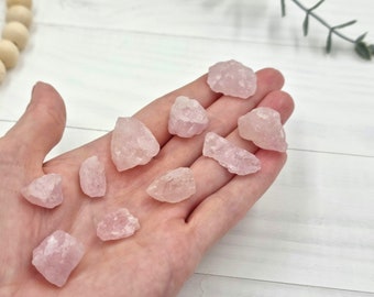 May include: A collection of ten small, pink rose quartz crystals. The crystals are rough and have a natural, unpolished look.