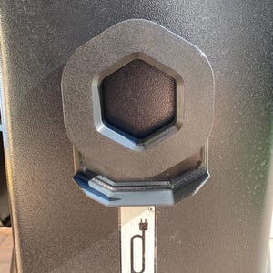 May include: A black electrical outlet with a hexagonal cover and a plug symbol.