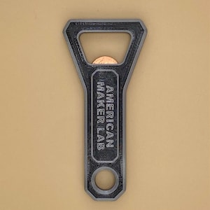 May include: A black metal bottle opener with the text "AMERICAN MAKER LAB" engraved on the handle.