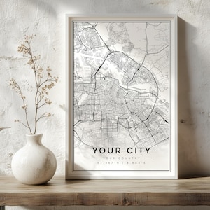 May include: A framed vertical wall art print featuring a black and white street map of a city. The print includes the text YOUR CITY, YOUR COUNTRY, and the coordinates 52.367 N | 4.904 E centered at the bottom within a thin black border.