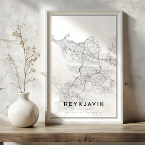 Op de afbeelding: Een ingelijste wandkunstprint met een zwart-wit stadsplattegrond van Reykjavik, IJsland. De print bevat de stadsnaam in dikke hoofdletters, de landnaam en de geografische coördinaten 64.135 N | 21.895 W aan de onderzijde.