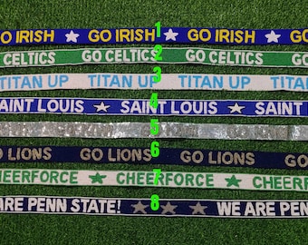 Puede incluir: Una colección de ocho cintas bordadas con nombres de equipos y frases. Las cintas presentan textos como "GO IRISH", "GO CELTICS", "TITAN UP", "SAINT LOUIS", "GO LIONS", "CHEERFORCE" y "WE ARE PENN STATE!" en varios colores.