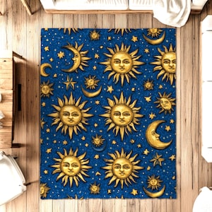 Könnte beinhalten: Ein blauer Teppich mit einem himmlischen Design mit goldenen Sonnen, Monden und Sternen. Die Sonnen haben detaillierte Gesichter, und die Sterne sind über den Hintergrund verstreut. Der Teppich ist rechteckig und scheint aus einem weichen Material zu sein.