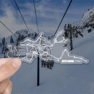 May include: A white sticker with a line drawing of a ski resort map, showing the trails and lifts. The sticker says "Alta Badia | Italy".