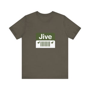 Puede incluir: Una camiseta verde oscuro con un cuadrado blanco en la parte delantera. El cuadrado tiene la palabra "Jive" en letras blancas y dos siluetas de patos verdes a cada lado de una parrilla de jeep blanca.