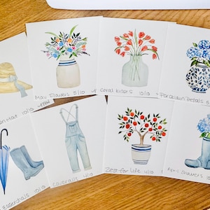 May include: Watercolor paintings of spring and summer themes. Includes a garden hat, flowers in vases, overalls, an umbrella, rain boots, and a potted tree. Each painting has a title and date.