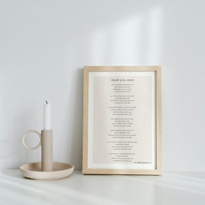 Puede incluir: Una impresi&oacute;n enmarcada con un poema titulado "Gracias, mam&aacute;" en un marco de madera claro sobre una superficie blanca con un candelero beige y una vela blanca.
