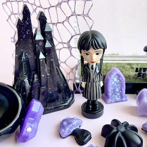 Close-up of handmade gothic castle décor and Wednesday Addams figure for jumping spider enclosure.