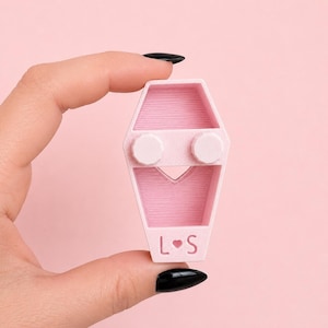 Hand holding the back of a magnetic jumping spider coffin hide showing the open hollow design.
