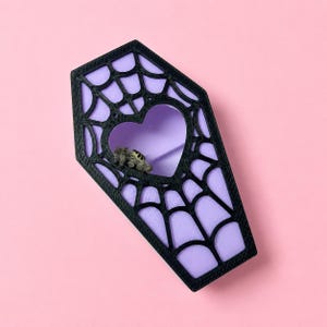 Purple magnetic jumping spider coffin hide with a jumping spider resting inside the heart-shaped entrance.