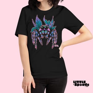 May include: Black t-shirt with a colorful jumping spider graphic. The spider has iridescent blue and green wings and pink legs. The text "Little Spoods" is printed in pink below the spider.