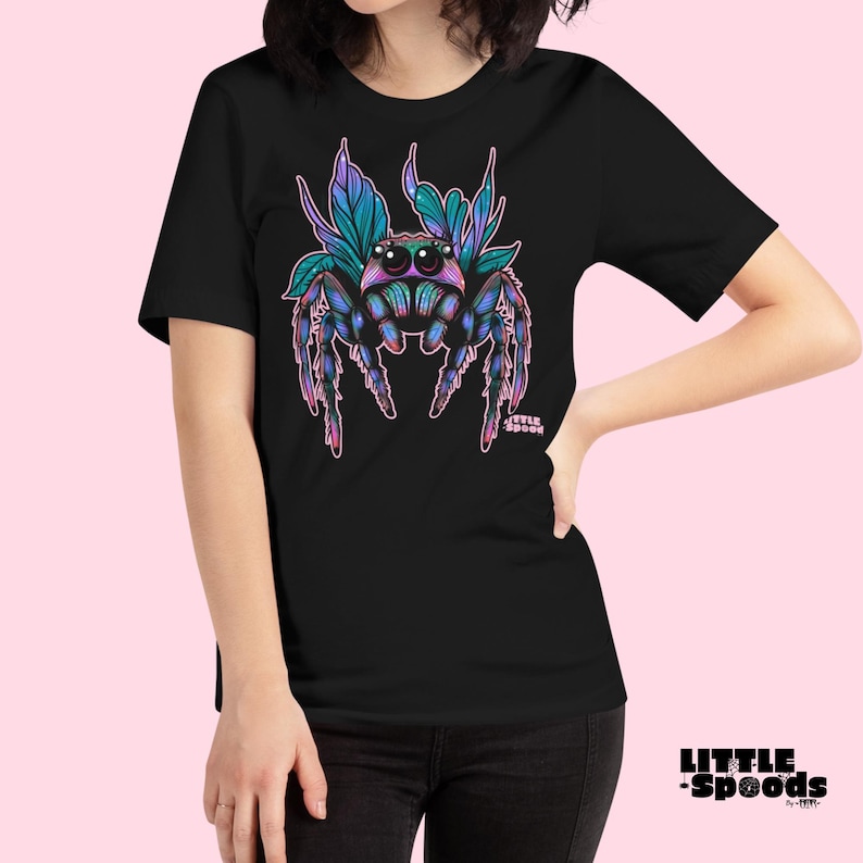 May include: Black t-shirt with a colorful jumping spider graphic. The spider has iridescent blue and green wings and pink legs. The text "Little Spoods" is printed in pink below the spider.