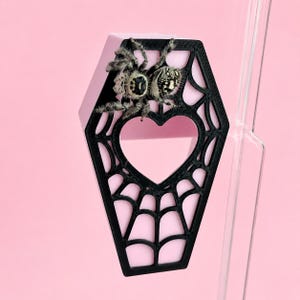 Jumping spider peeking out from a purple magnetic coffin hide with a heart-shaped entrance and black spiderweb design.