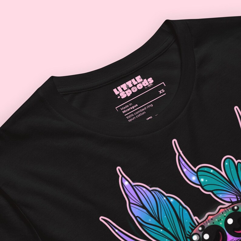 May include: Black t-shirt with a colorful graphic of a creature with wings. The shirt has a pink tag that says "Little Spoods" and "Made in Nicaragua 100% combed ring spun cotton XS".