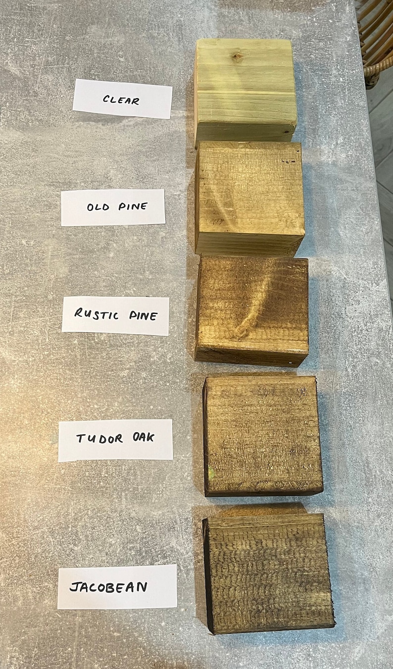 May include: Five wood samples stained in different colors: clear, old pine, rustic pine, tudor oak, and jacobean. The samples are arranged vertically from top to bottom.