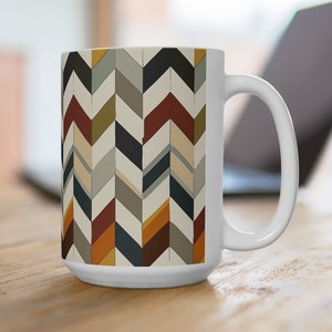 May include: White ceramic mug with a geometric pattern of colorful chevron shapes in shades of brown, yellow, orange, red, gray, and blue.