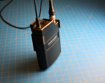 May include: A black Radio Shack wireless microphone transmitter with a black antenna and a black cable attached.