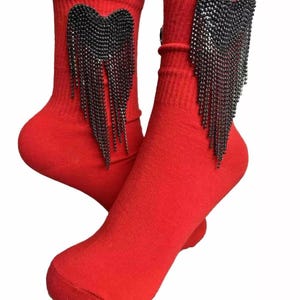 May include: A pair of red ankle socks with a black rhinestone heart with a fringe detail.