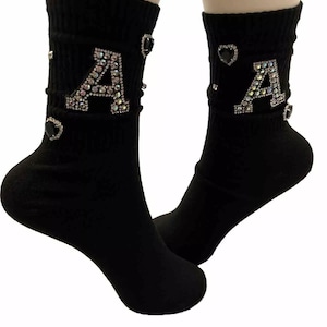 May include: Black socks with a large rhinestone letter A on each sock. The letter A is surrounded by smaller rhinestones and black hearts.
