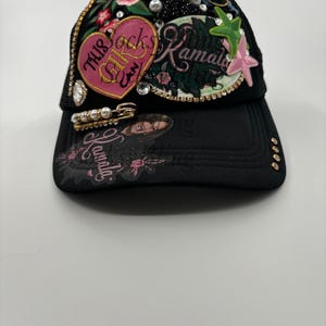 May include: Black mesh trucker hat with a pink heart patch that says "This Girl Can Rock" and a black and white patch that says "The Kamala Harris"